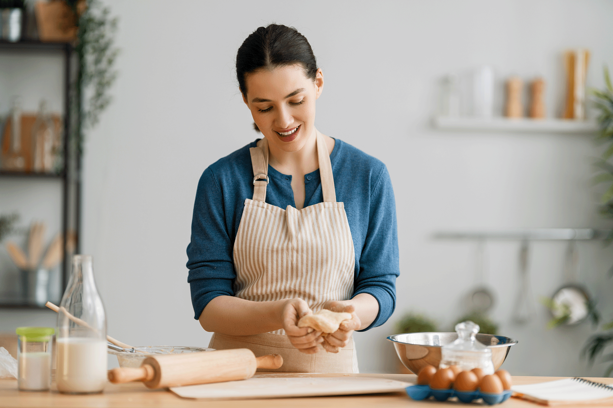 Kate Reilly, founder of Taste This Plate, smiling as she gently kneads fresh dough on a wooden countertop in her kitchen.