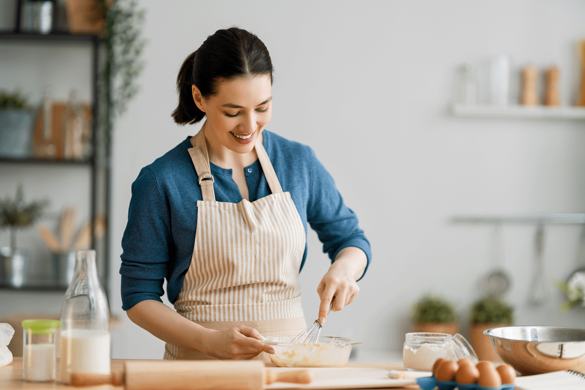 A happy Kate Reilly whisking batter in a glass bowl, demonstrating a recipe step for her blog, Taste This Plate.