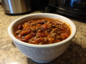 A close-up of a white bowl filled with delicious 30-minute chili, featuring ground beef, kidney beans, and diced tomatoes.