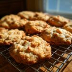 A close-up of freshly baked apple pie cookies cooling on a wire rack, showcasing their textured surface and golden-brown color.