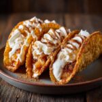 Three crispy blueberry breakfast quesadilla tacos filled with blueberries and topped with whipped cream and cinnamon.