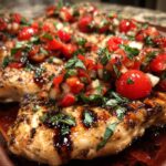 Close-up of grilled Bruschetta chicken breasts topped with a fresh tomato, basil, and onion mixture.