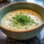Close-up of a bowl of creamy soup topped with fresh chives, perfect for carrot banana muffins.