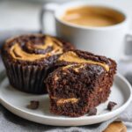 A decadent chocolate protein mug cake, swirled with peanut butter and cut in half to reveal the moist interior.