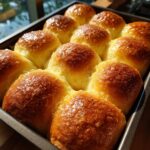 Close-up of freshly baked cranberry sugar cookies rolls in a baking pan, golden brown and glistening.