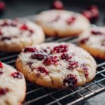 Close-up of festive cranberry sugar cookies, dusted with sugar and studded with cranberries, cooling on a rack.