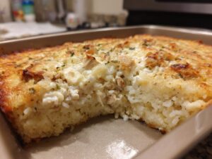 A close-up of a slice of green chile chicken and rice casserole, showing fluffy rice, tender chicken, and a cheesy topping.