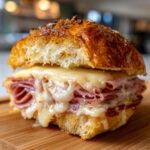 Close-up of a delicious Ham and Cheese Slider with melted cheese oozing out, on a wooden board.