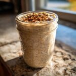 A close-up of high protein overnight oats in a mason jar, topped with cinnamon.