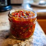 Close-up of a glass jar filled with vibrant homemade tomato salsa, perfect for canning.