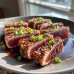 Close-up of seared ahi tuna steaks coated in sesame seeds and sliced, garnished with green onions.