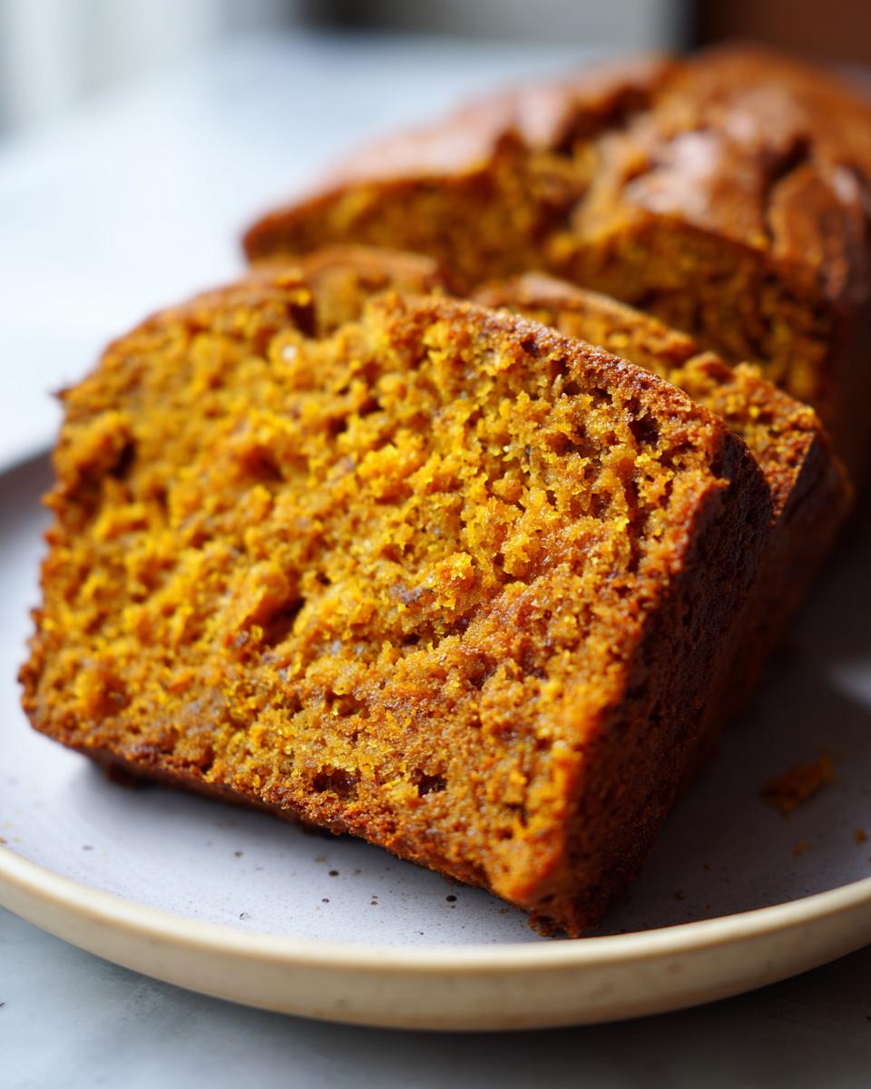 Close-up of moist, golden-brown sourdough pumpkin bread slices on a plate.