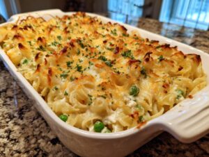Close-up of a golden-brown baked Tuna Casserole with noodles, peas, and melted cheese, garnished with parsley.