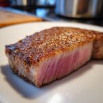 Close-up of a perfectly cooked tuna steak, showing a beautiful pink interior and seared crust.