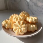 A plate of golden-brown whipped shortbread cookies with delicate fluted edges, perfect for a tea time treat.