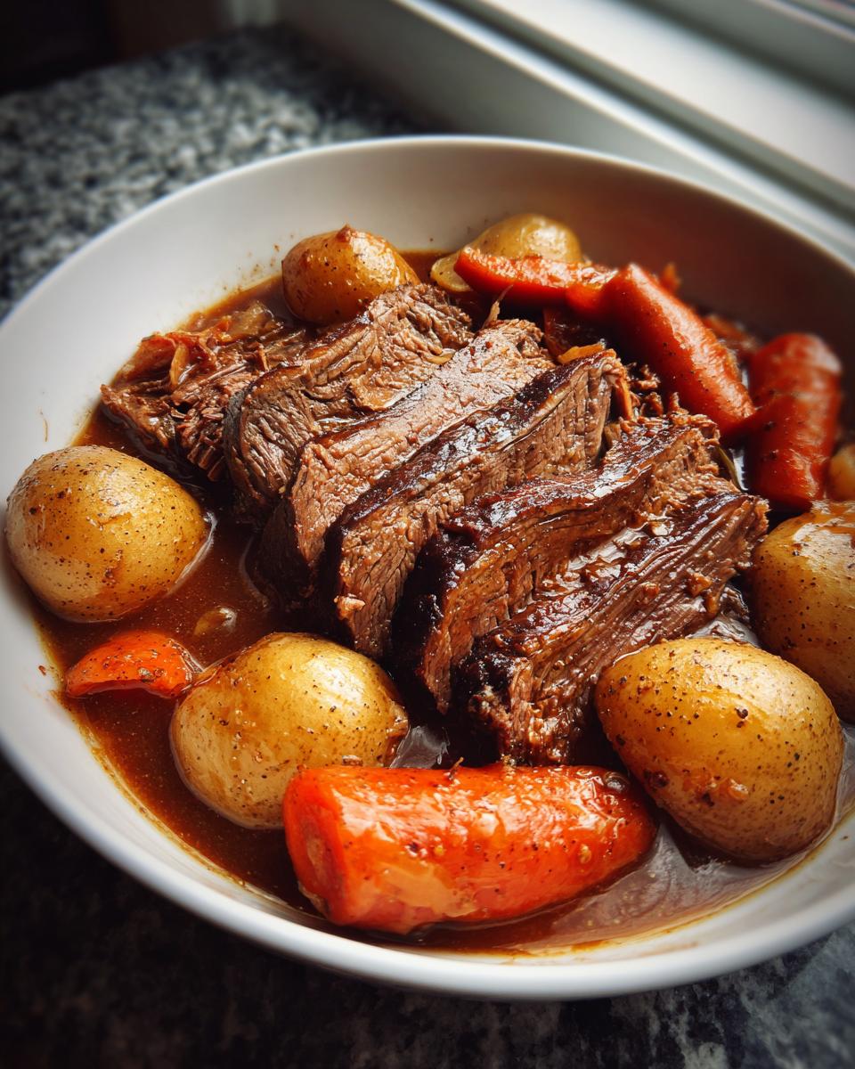 Close-up of tender, sliced pot roast served in a white bowl with whole potatoes and carrots in rich brown gravy.