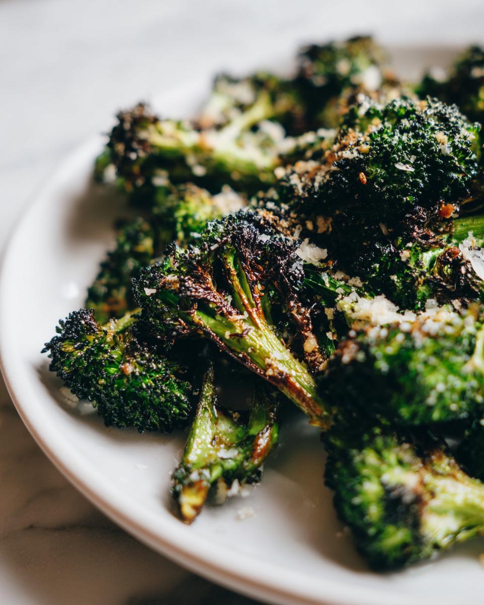 Close-up of perfectly cooked roasted broccoli florets, slightly charred and topped with grated Parmesan cheese.