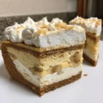 Close-up of a thick slice of banana cream cheesecake showing graham cracker crust, banana slices, cream cheese layers, and whipped topping.