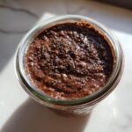 Overhead view of rich chocolate overnight oats in a glass jar, topped generously with chia seeds.
