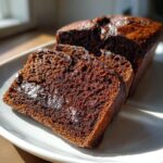 Close-up of three thick slices of dark, moist hot fudge brownie bread resting on a white plate.