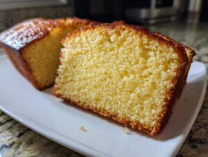 A thick slice of moist, yellow million dollar pound cake showing its dense, buttery crumb texture.