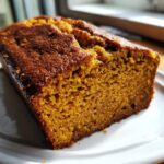Close-up of a moist slice of homemade pumpkin bread showing its rich orange color and soft crumb.