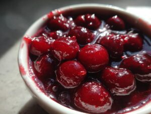 Close-up of shiny, deep red whole cherries suspended in thick syrup, representing homemade cherry pie filling.