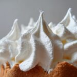 Close-up of stiff, white royal icing piped into sharp peaks, resembling gingerbread house icing.