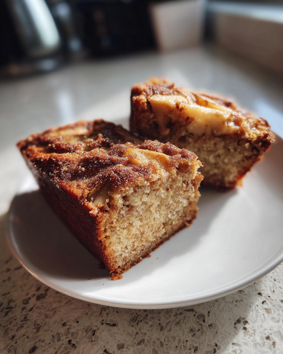 Two moist slices of Swedish apple cake with a cinnamon sugar topping served on a white plate.