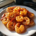 A pile of perfectly seasoned and cooked air fryer frozen shrimp served on a white plate.