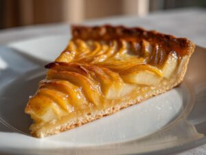 Close-up of a perfect slice of amazing apple tart showing layered, glazed fruit on a crisp crust.