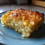 A close-up of a square slice of creamy, baked funeral potatoes recipe with a crispy, golden-brown top.