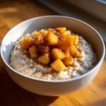Close-up of a bowl of creamy apple cinnamon oatmeal topped generously with caramelized, spiced apple chunks.