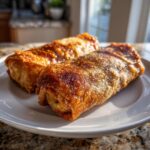 Two golden-brown, crispy Baked Chicken Chimichangas resting on a white plate.