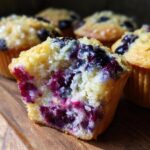 Close-up of a halved cream cheese muffin showing moist interior packed with blueberries.