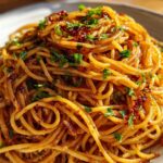 A close-up, appetizing shot of caramelized onion pasta tossed in a savory sauce and garnished with fresh parsley.