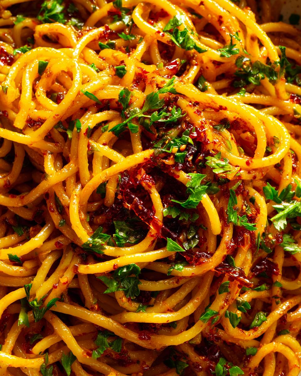 Close-up of glossy spaghetti tossed with rich caramelized onion sauce and fresh parsley.