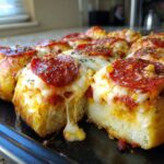 Close-up of freshly baked pepperoni pizza sliders with melted, stretching cheese.
