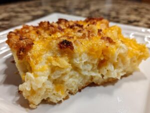 Close-up of a cheesy, baked slice of funeral potatoes recipe with a crispy, browned topping.