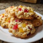 A stack of homemade fruitcake cookies featuring bright red and yellow candied fruit pieces.