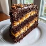 A decadent slice of chocolate caramel toffee crunch cake featuring multiple dark chocolate layers and gooey caramel filling.