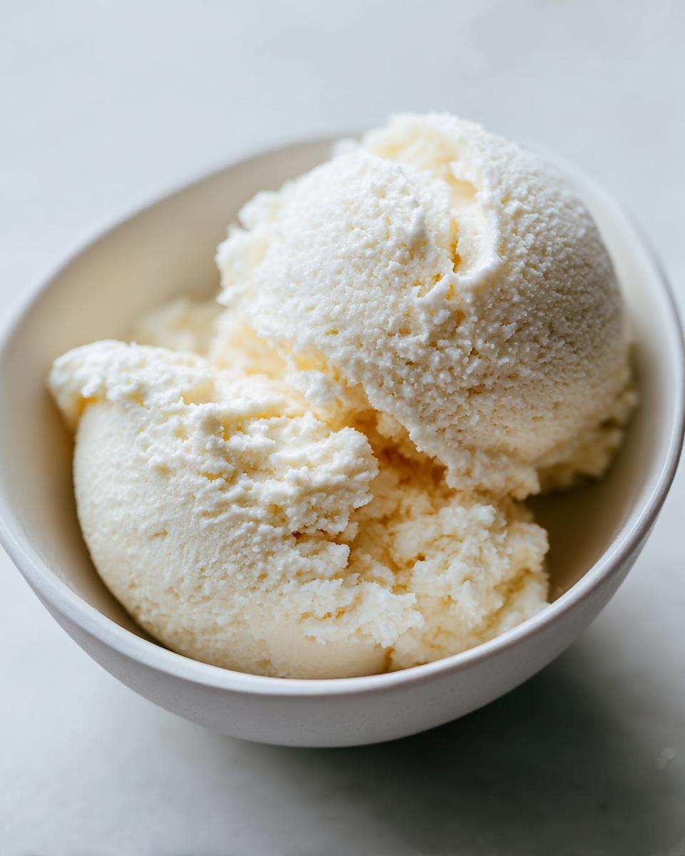 Close-up of three scoops of white, creamy cottage cheese ice cream in a small bowl.