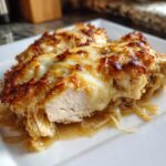 Close-up of juicy french onion chicken topped with bubbly, browned melted cheese.