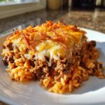 A hearty serving of french onion ground beef and rice casserole topped with melted cheese and crispy fried onions.