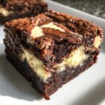 A close-up of a fudgy cream cheese brownies square with a rich chocolate base and a marbled cream cheese swirl.