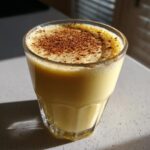 Close-up of a glass of creamy homemade eggnog, topped with a generous dusting of cinnamon.