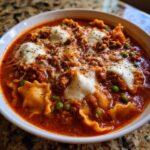Close-up of a hearty bowl of instant pot lasagna soup topped with melted mozzarella and herbs.