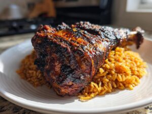 A close-up of a piece of dark, glazed Jamaican jerk chicken resting on a bed of seasoned rice on a white plate.