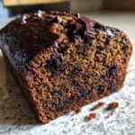 Close-up of a slice of moist chocolate banana bread showing rich texture and melted chocolate chips.