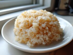 Close-up of a perfectly shaped mound of glistening sushi rice served on a small white plate.